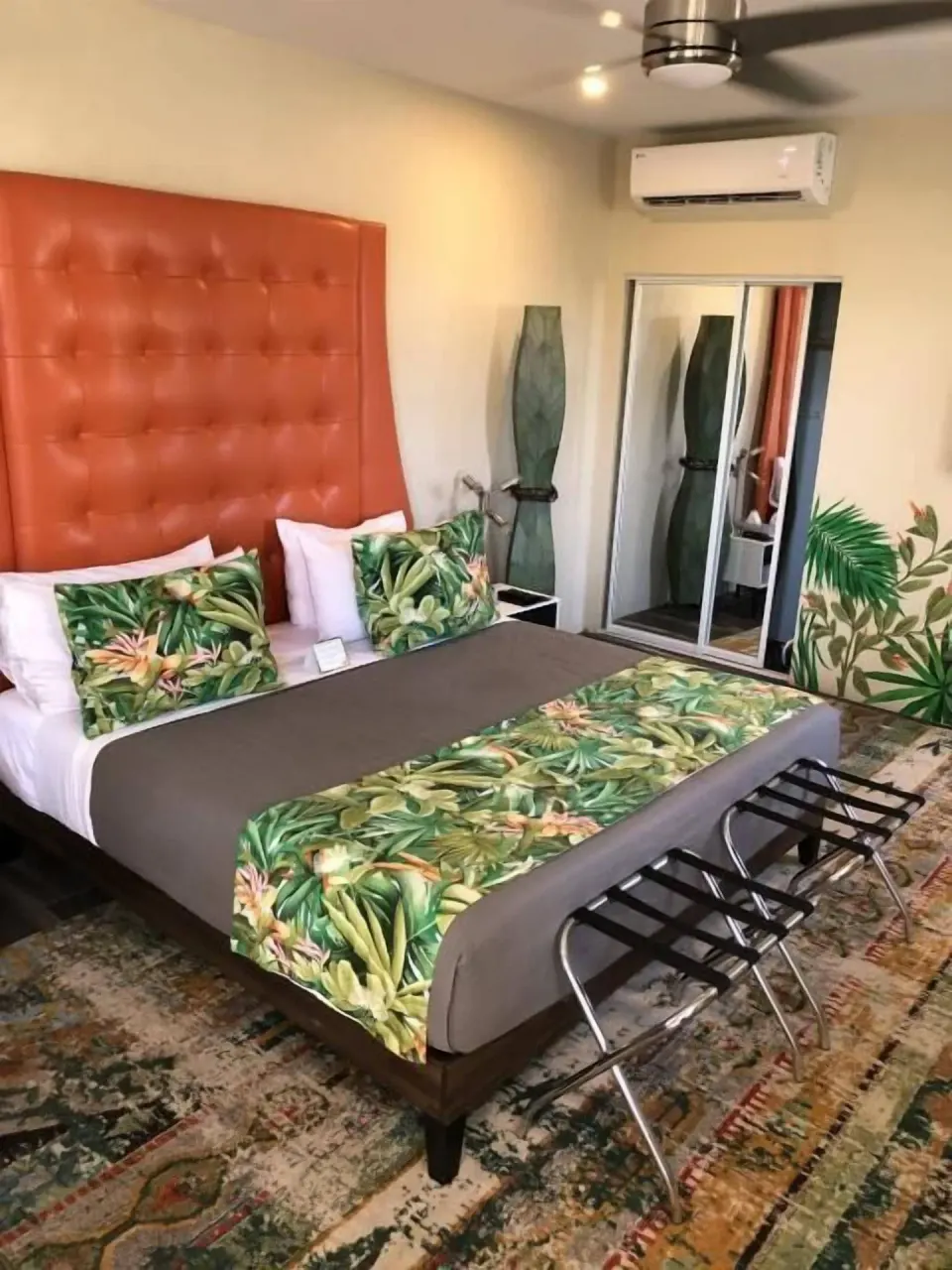 Signature Room Garden View king bed with tropical bedding and orange headboard at The Fred.