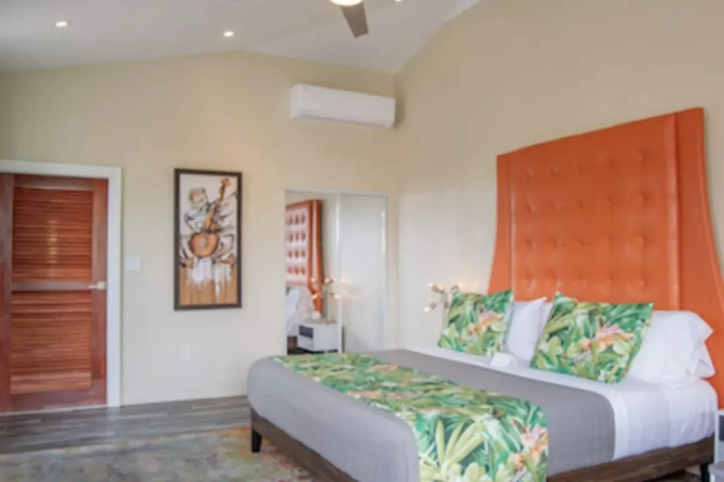 Signature Room king bed with orange headboard and tropical pillows at The Fred.
