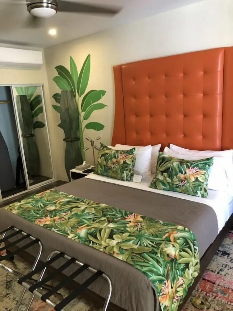 Standard Room Sherri bed with leafy pillows and botanical wall art at The Fred.