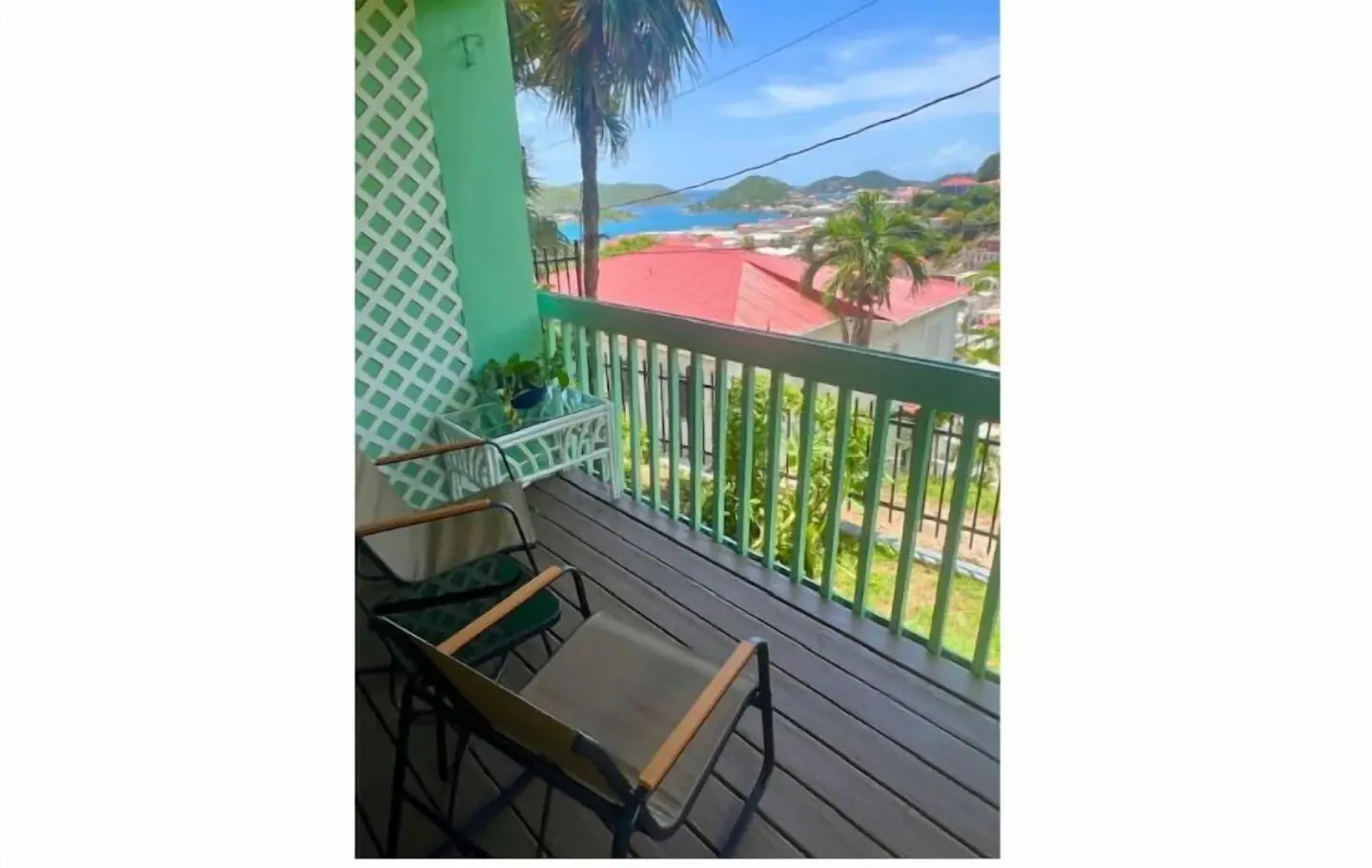 Balcony with chairs and a distant water view at The Green Iguana Hotel.