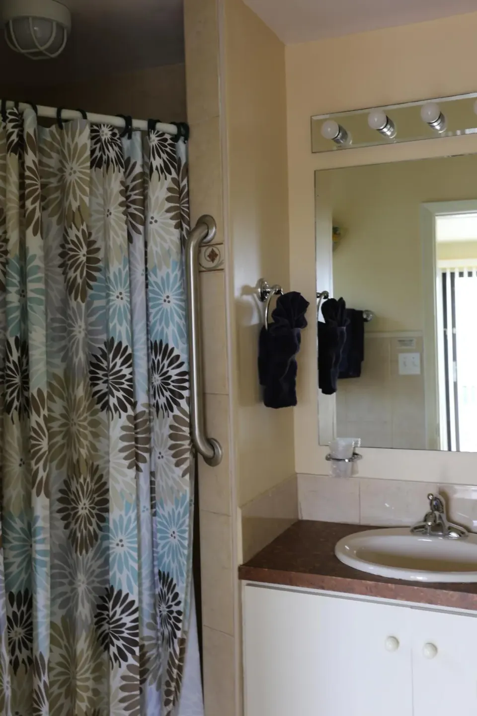 Bathroom with floral shower curtain and vanity at The Green Iguana Hotel.