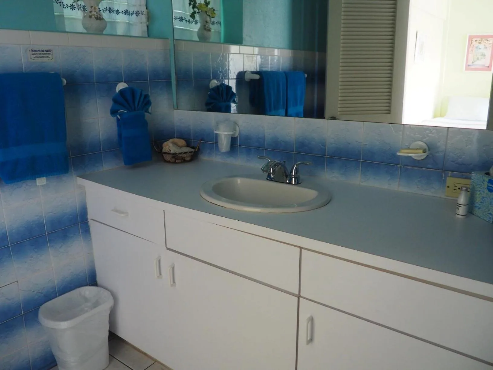 Blue-tiled bathroom vanity with sink and towels at The Green Iguana Hotel.