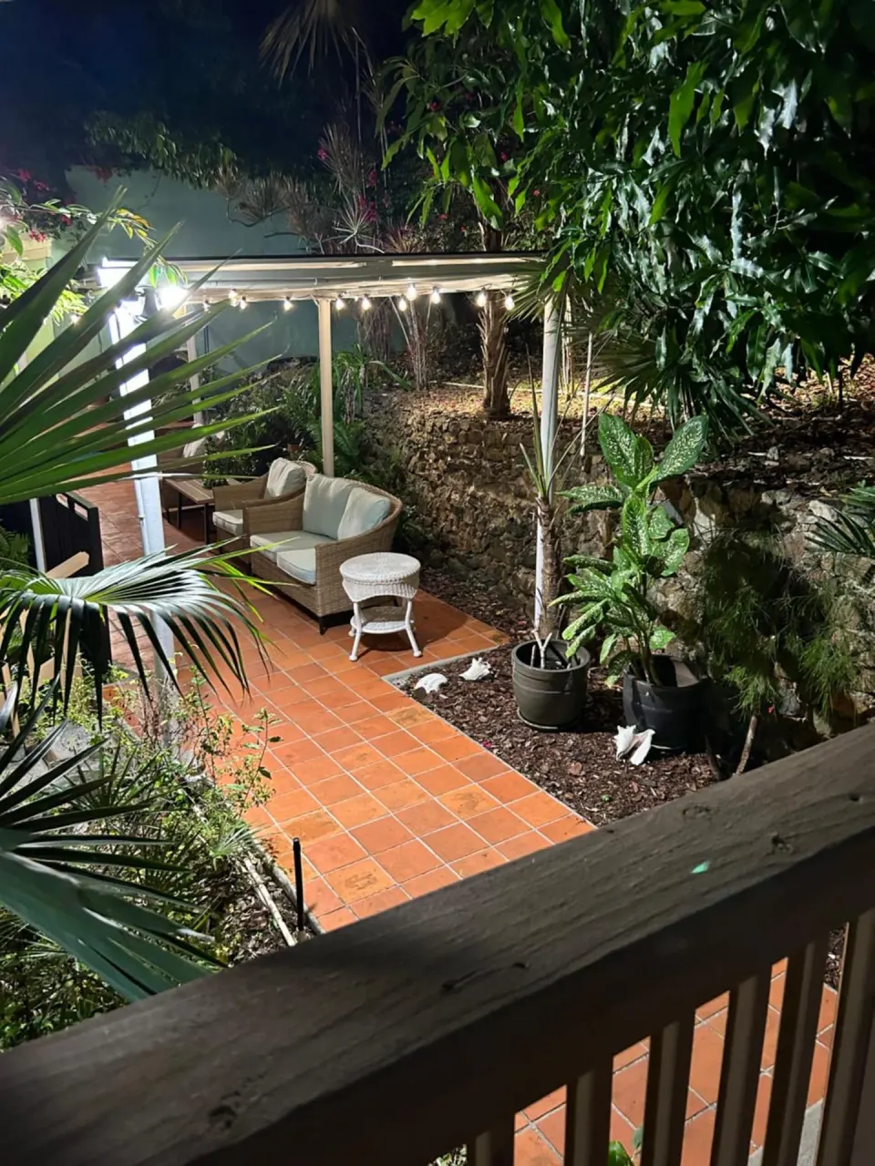 Night garden patio with string lights and seating at The Green Iguana Hotel.
