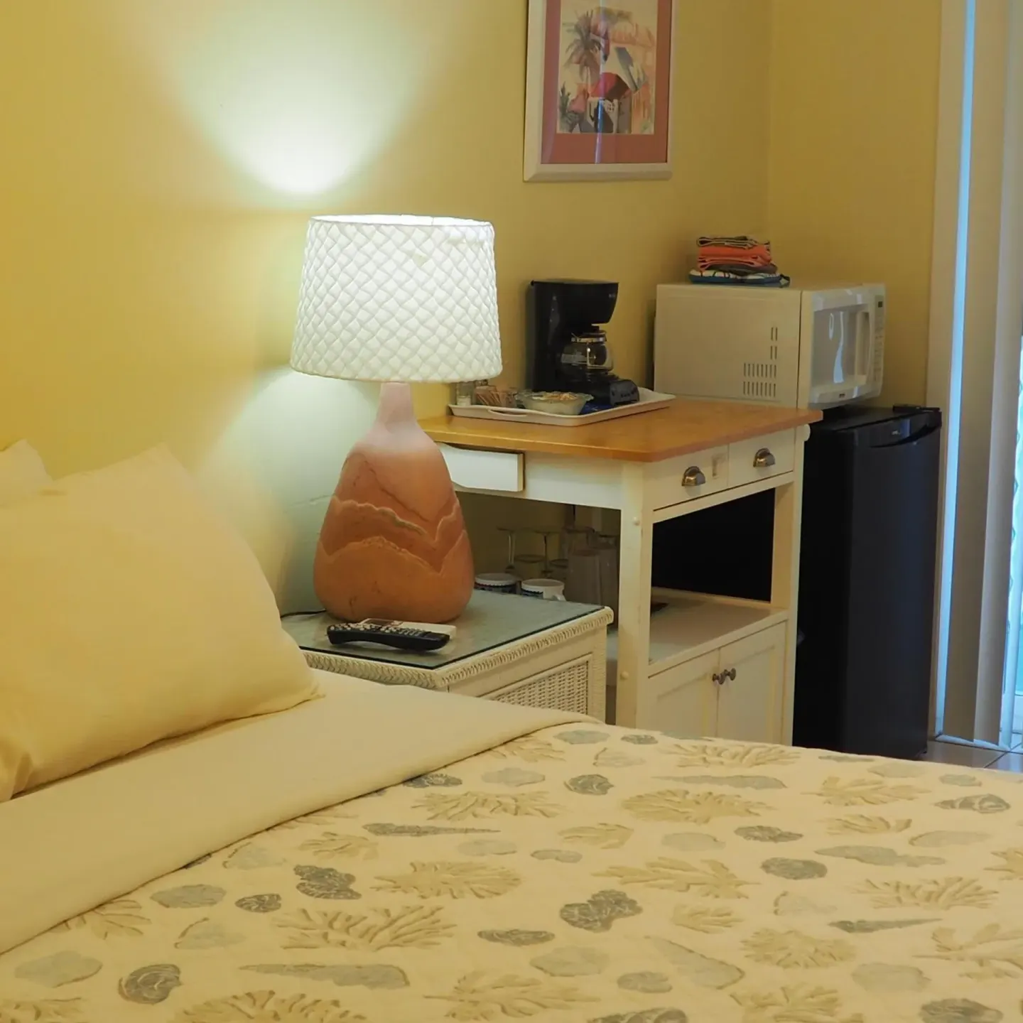 Bedside area with lamp, microwave, coffee maker, and mini fridge at The Green Iguana Hotel.
