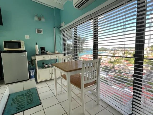 Guest room dining nook with mini fridge and wide window view at The Green Iguana Hotel.