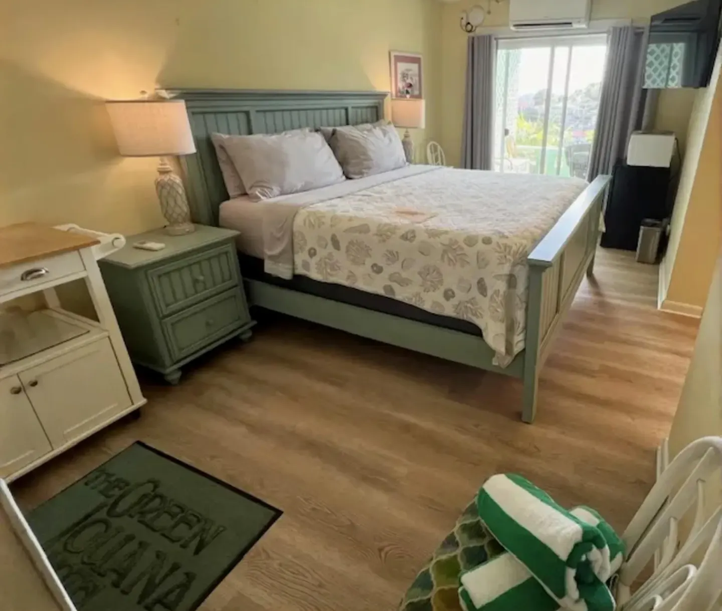 Guest room with green bed frame and sliding glass door at The Green Iguana Hotel.