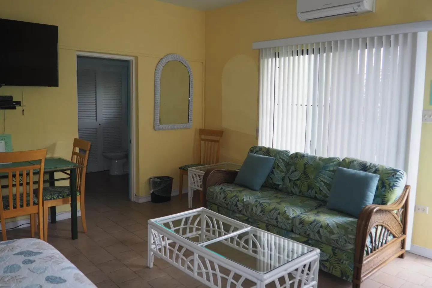 Guest room sitting area with sofa, dining table, and TV at The Green Iguana Hotel.