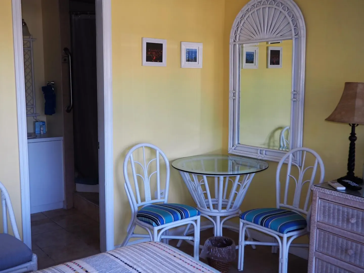 Guest room sitting area with wicker chairs and mirror at The Green Iguana Hotel.