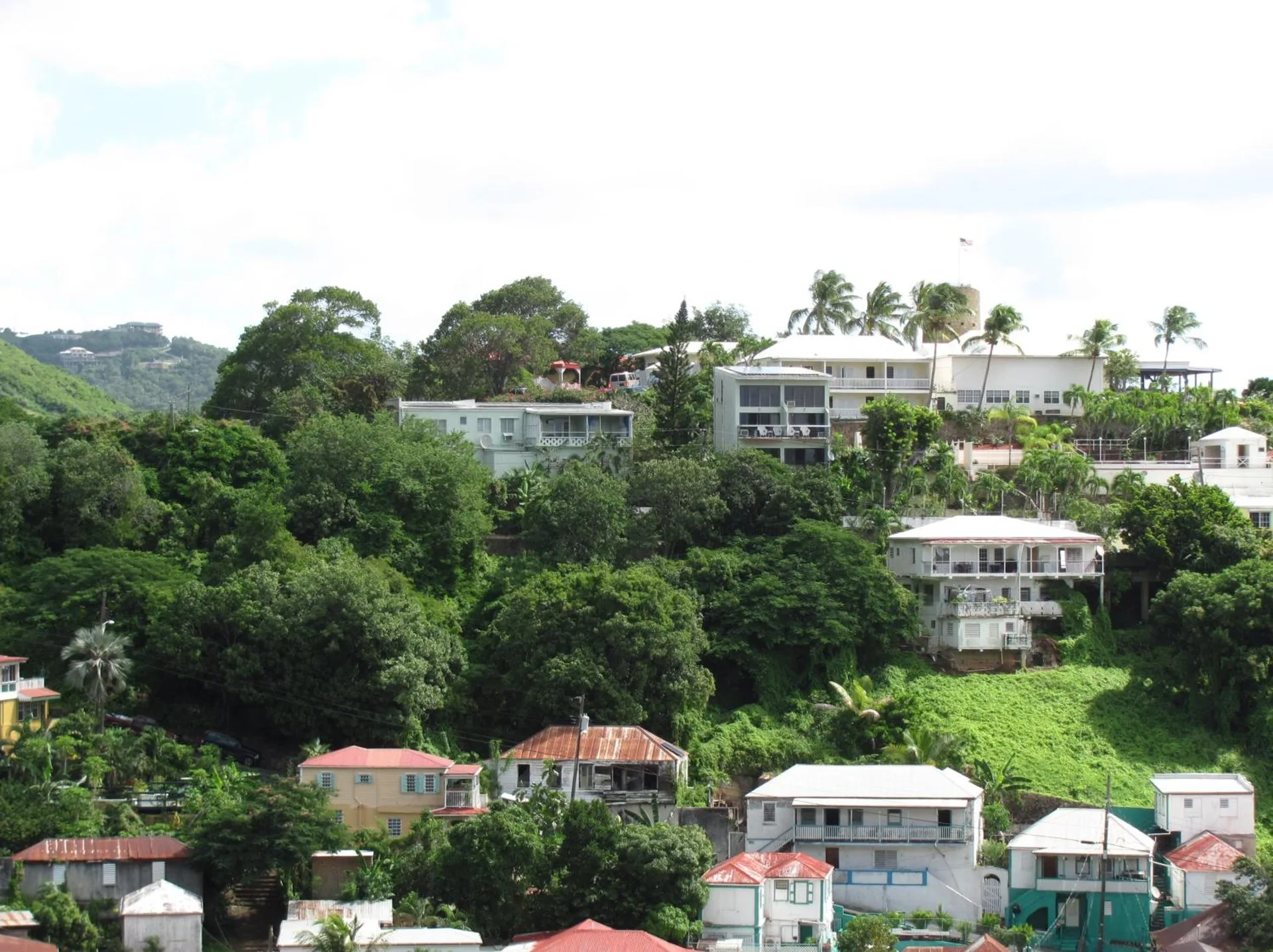 Hillside buildings and greenery around The Green Iguana Hotel.