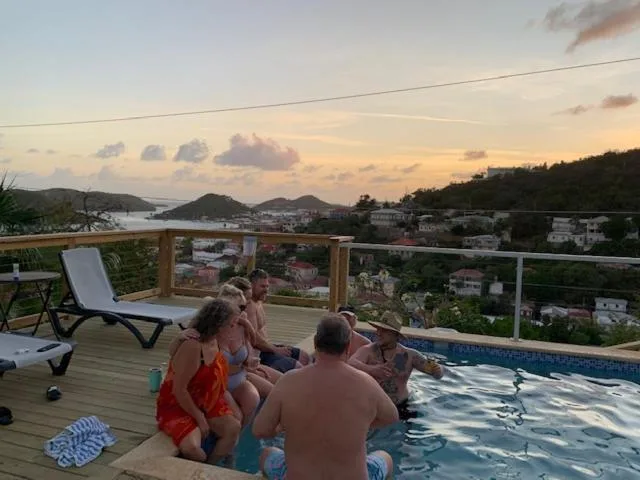 Guests sitting in the pool at sunset with hillside views at The Green Iguana Hotel.