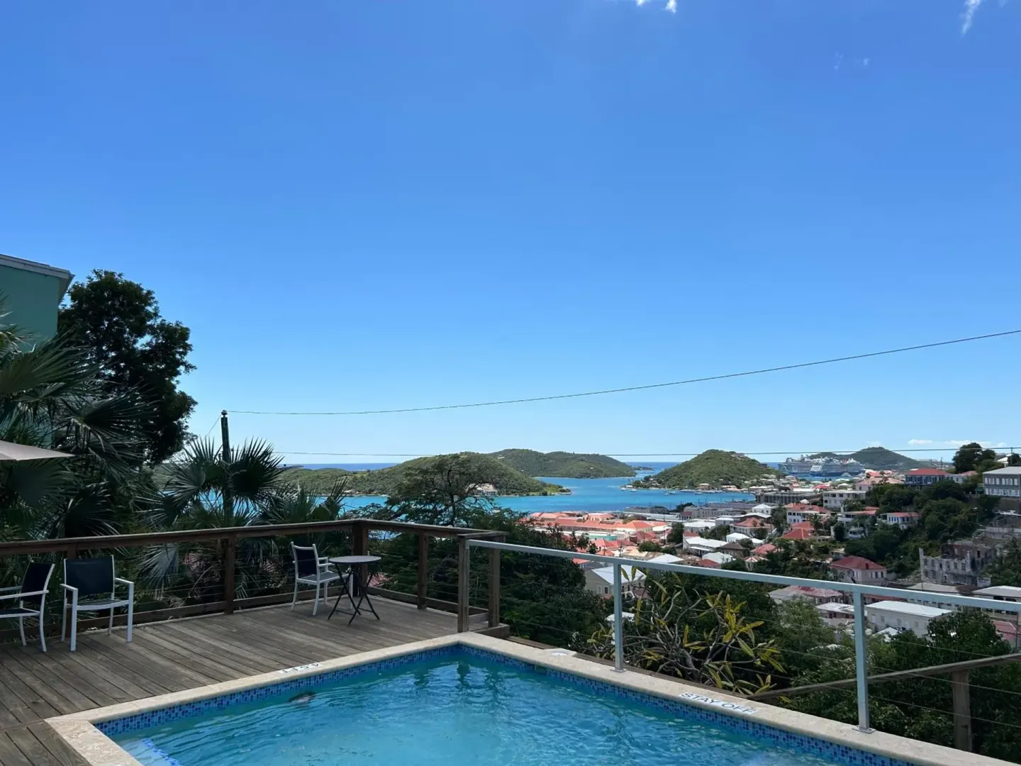 Pool deck with harbor and island views under a clear sky at The Green Iguana Hotel.