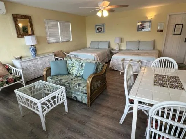 Studio room with two beds, wicker seating, and dining table at The Green Iguana Hotel.