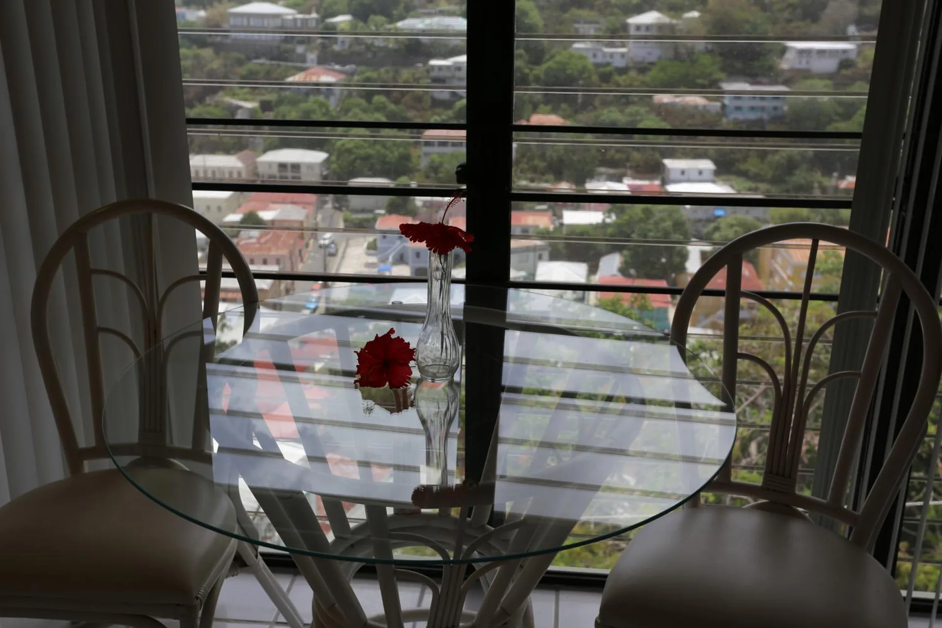 Glass dining table by a window with hillside view at The Green Iguana Hotel.