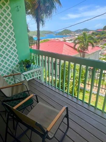 Studio balcony with chairs and hillside view at The Green Iguana Hotel.