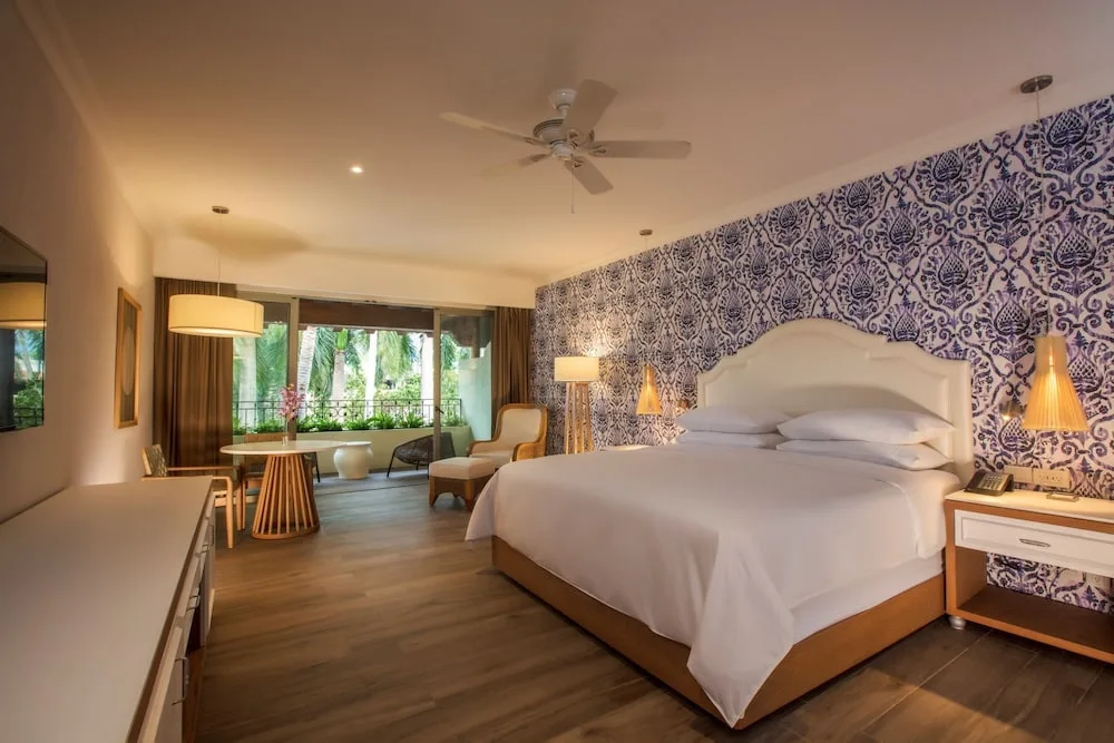 King guest room with patterned wall and balcony at The Hacienda at Krystal Grand Puerto Vallarta.