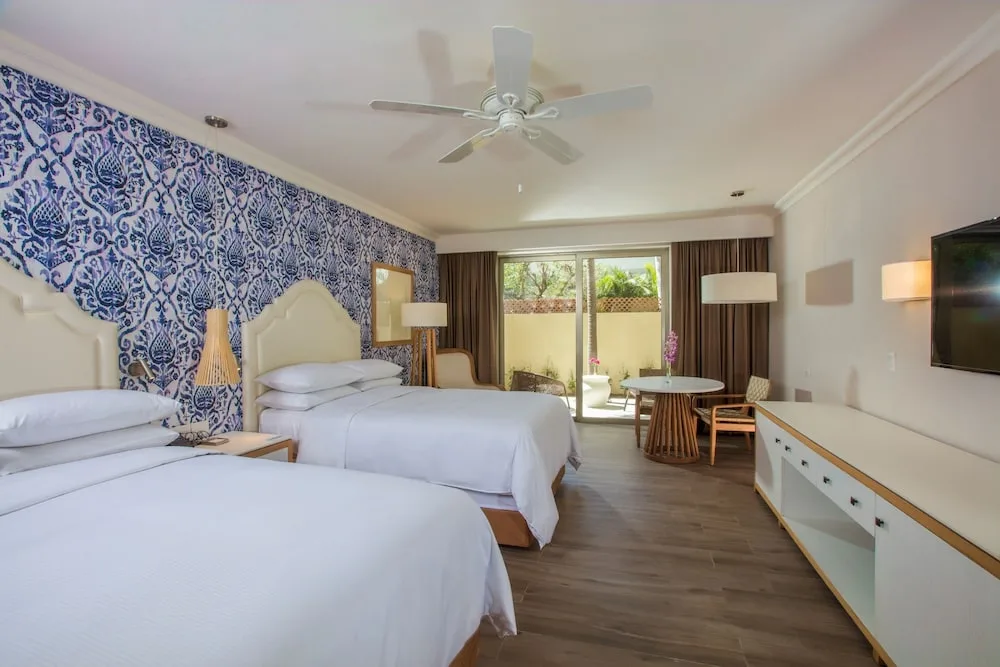 Two-bed guest room with patio doors at The Hacienda at Krystal Grand Puerto Vallarta.