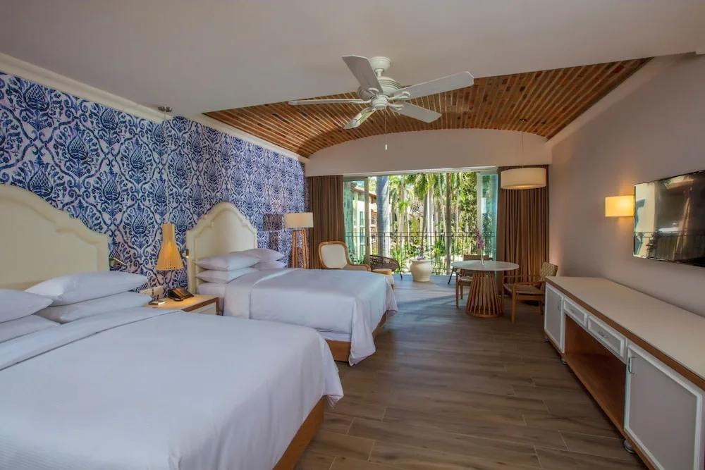 Guest room with two beds and balcony doors at The Hacienda at Krystal Grand Puerto Vallarta.