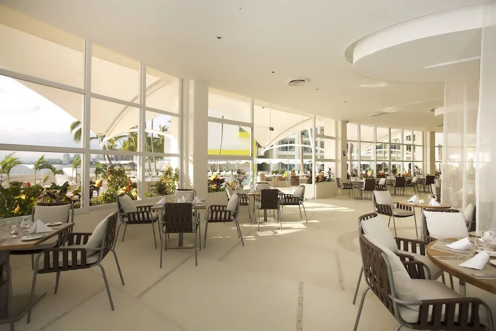 Bright dining room with ocean-facing windows at The Hacienda at Krystal Grand Puerto Vallarta.