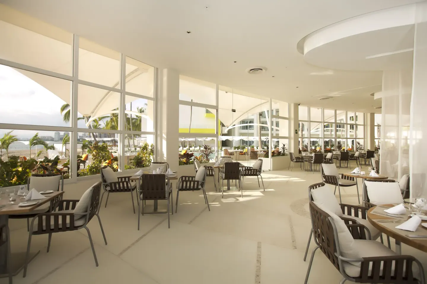 Bright restaurant dining room with window walls at The Hacienda at Krystal Grand Puerto Vallarta.