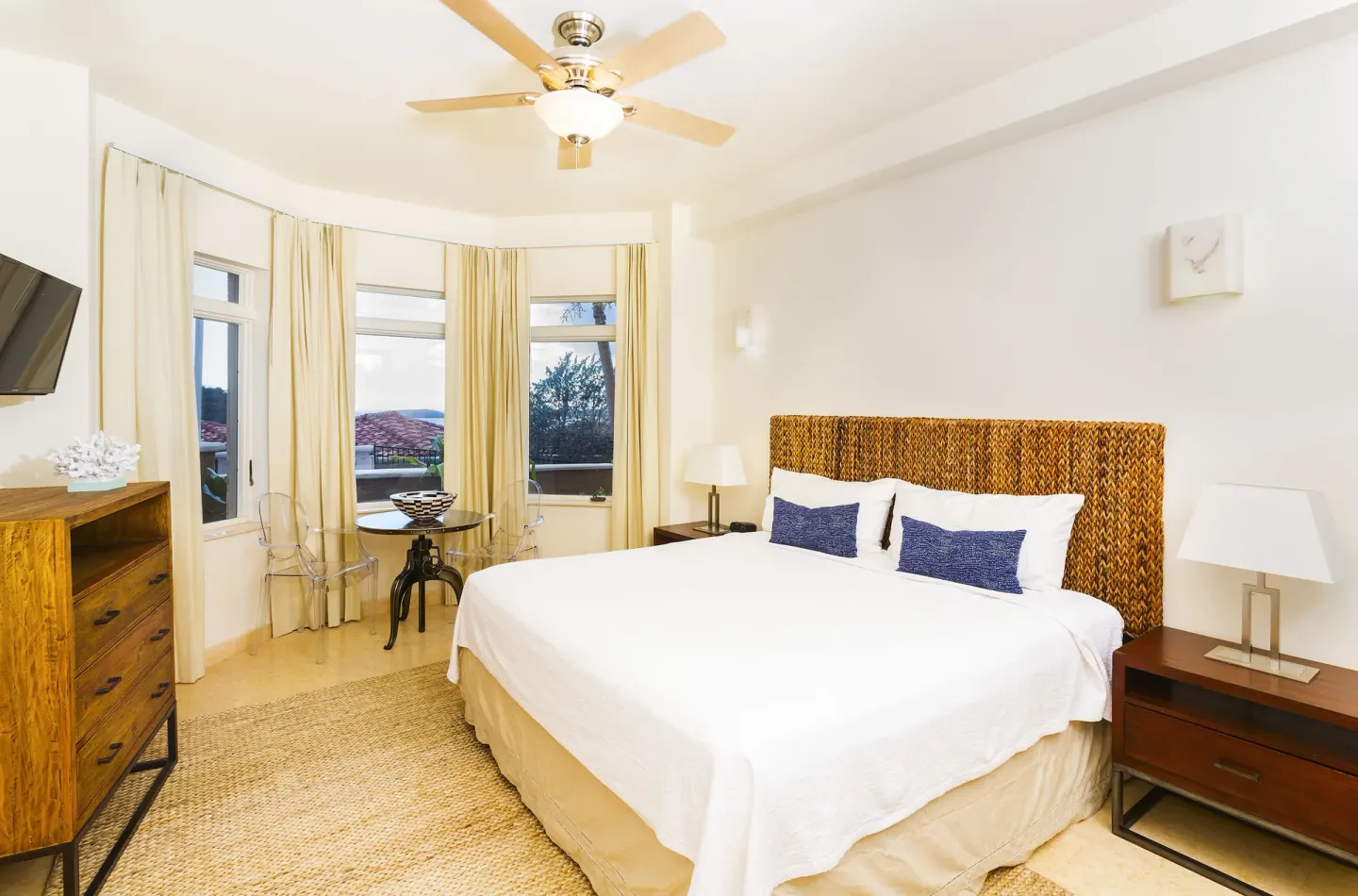 Guest room with king bed, dresser, and corner windows at The Hills, St John.