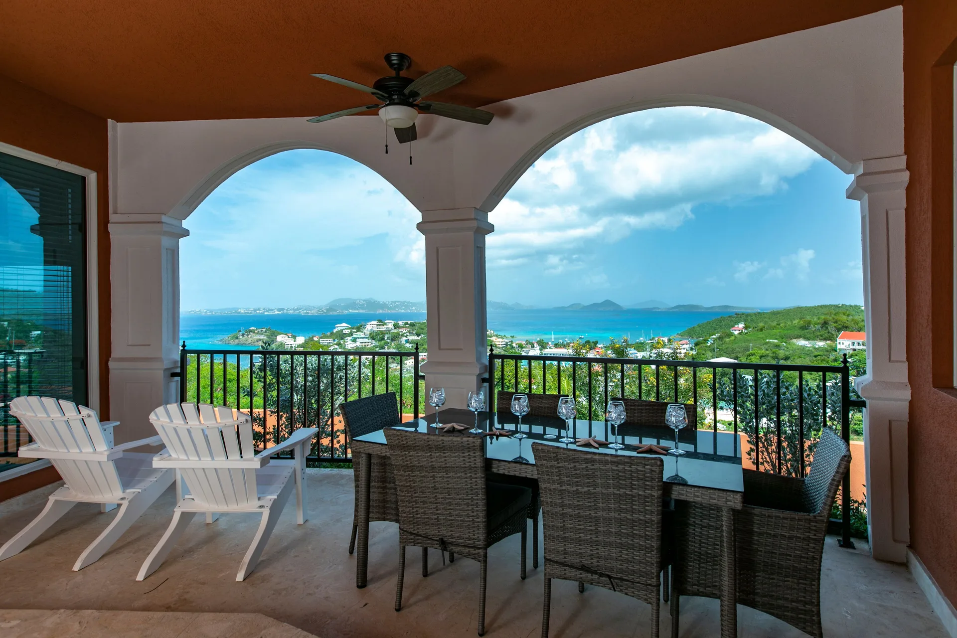 Covered terrace with dining table, lounge chairs, and sea view at The Hills, St John.