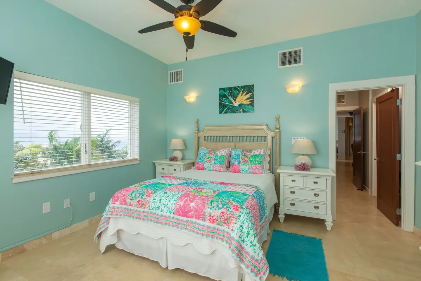 Guest room with floral bedding and palm-view window at The Hills, St John.