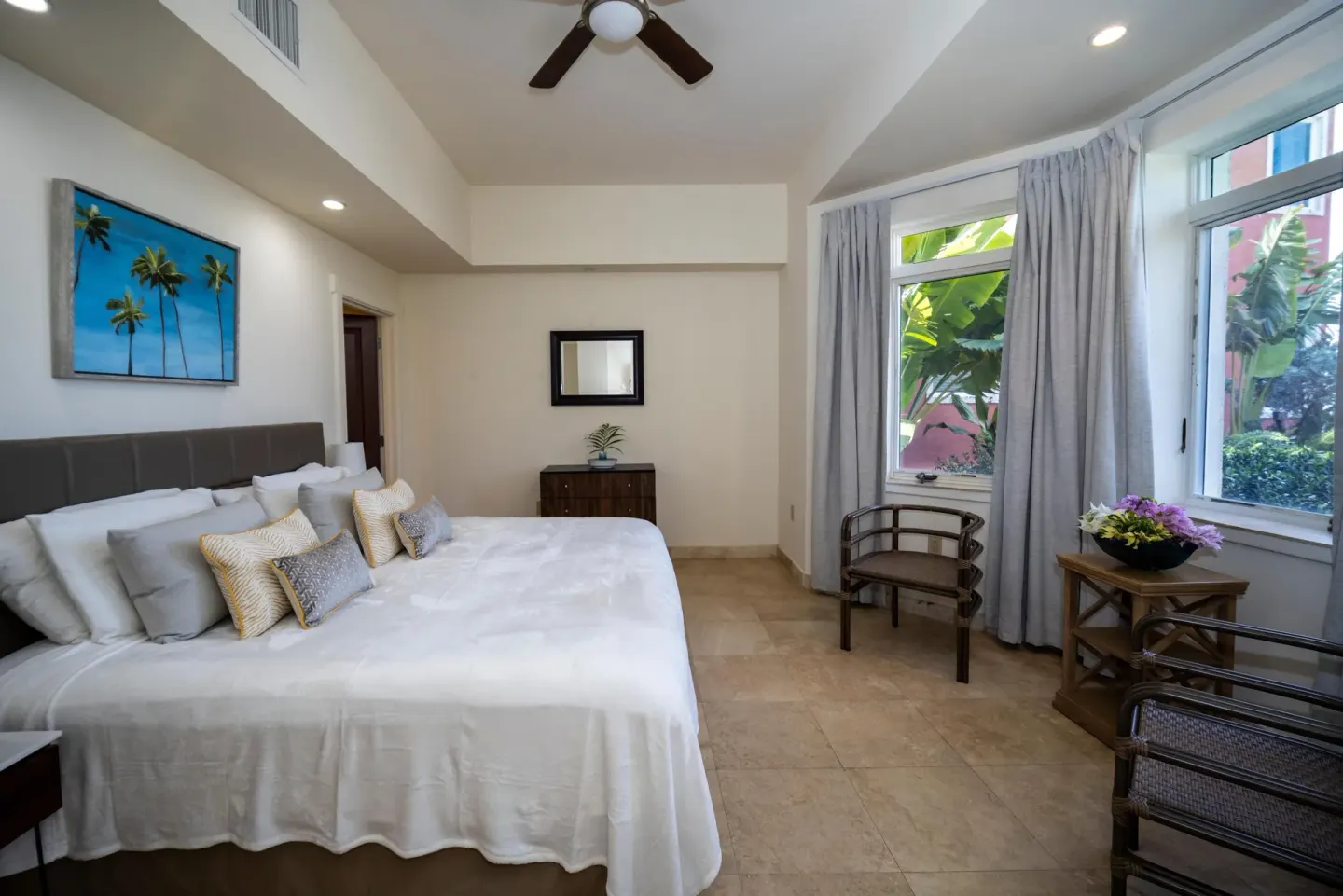 Guest room with white bed and garden-facing windows at The Hills, St John.