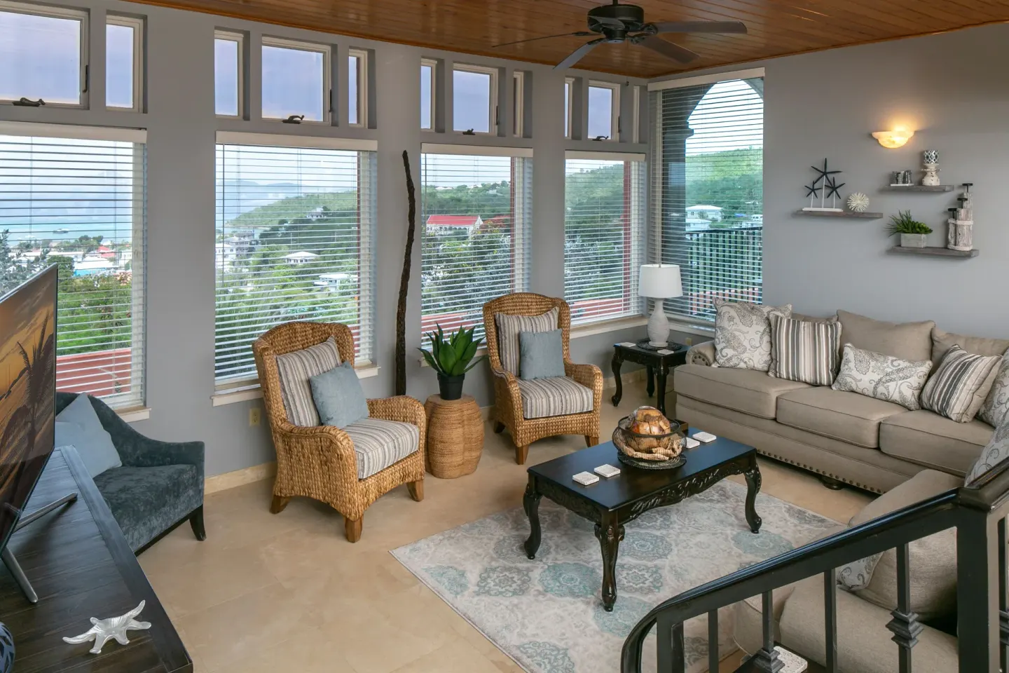 Living room with wicker chairs, sofa, and bay views at The Hills, St John.