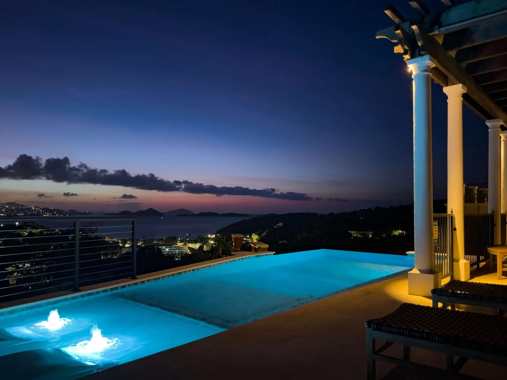 Nighttime infinity pool glowing blue above the bay at The Hills, St John.