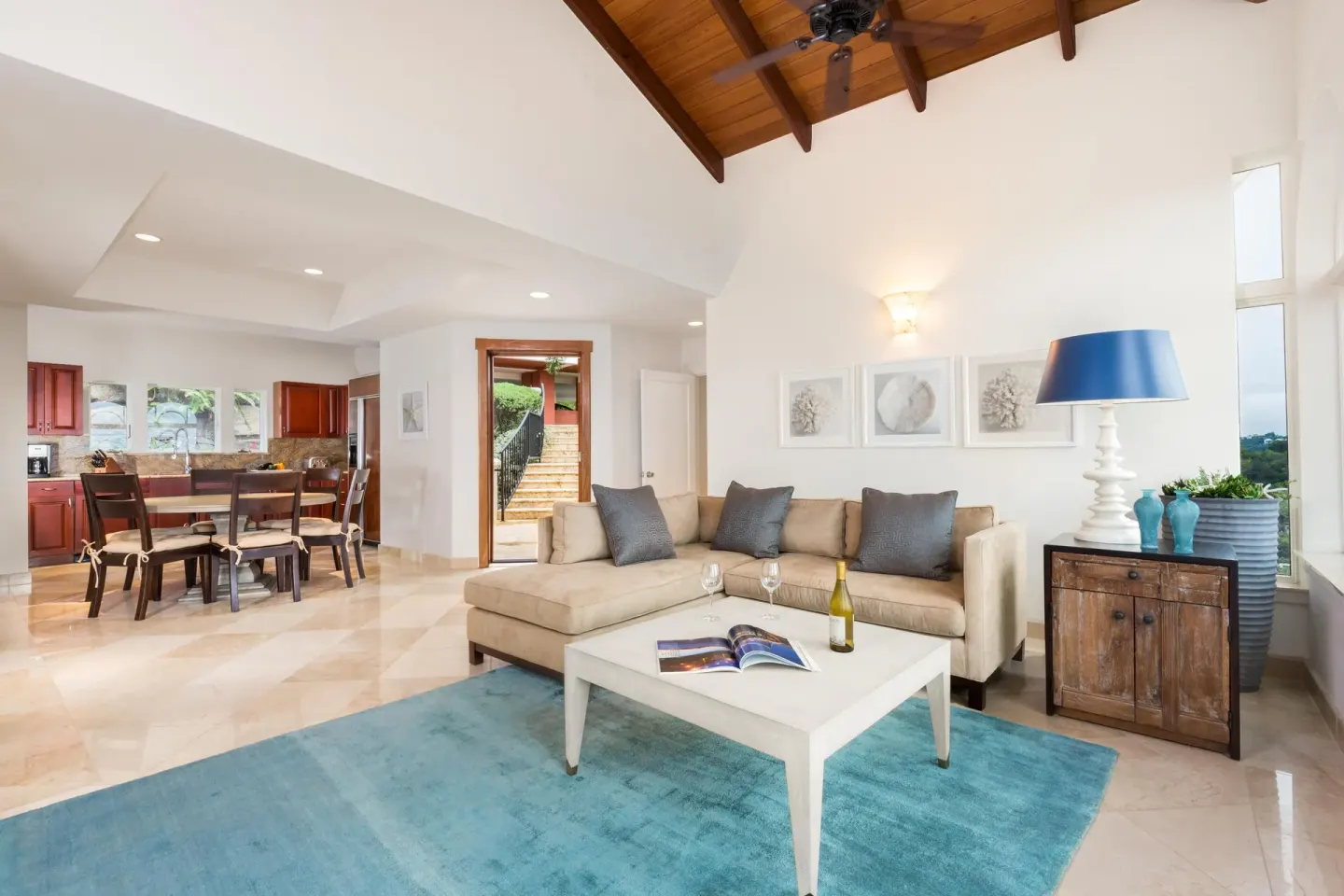 Open living room with sectional sofa, kitchen, and blue rug at The Hills, St John.
