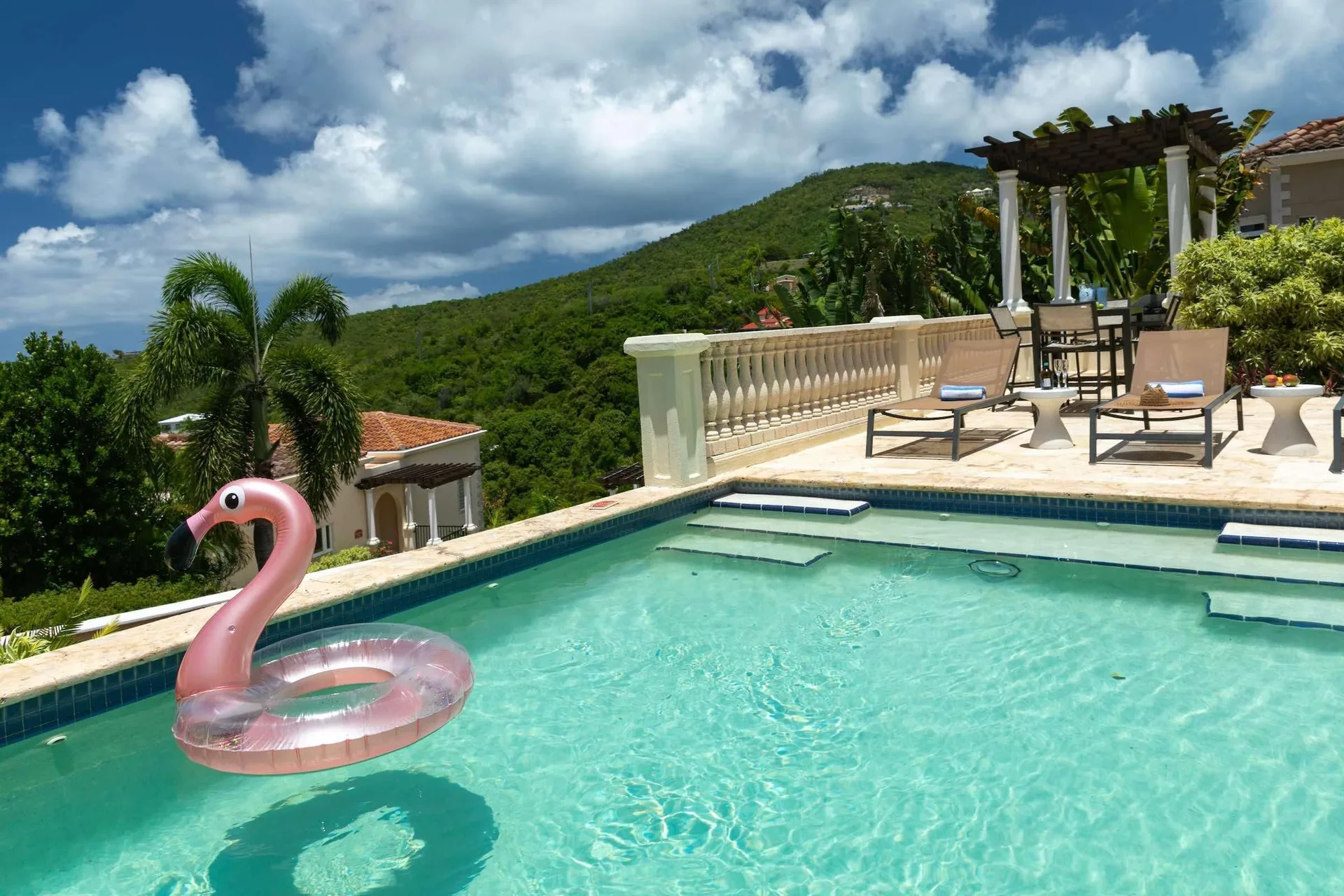 Pool with flamingo float, loungers, pergola, and hillside view at The Hills, St John.
