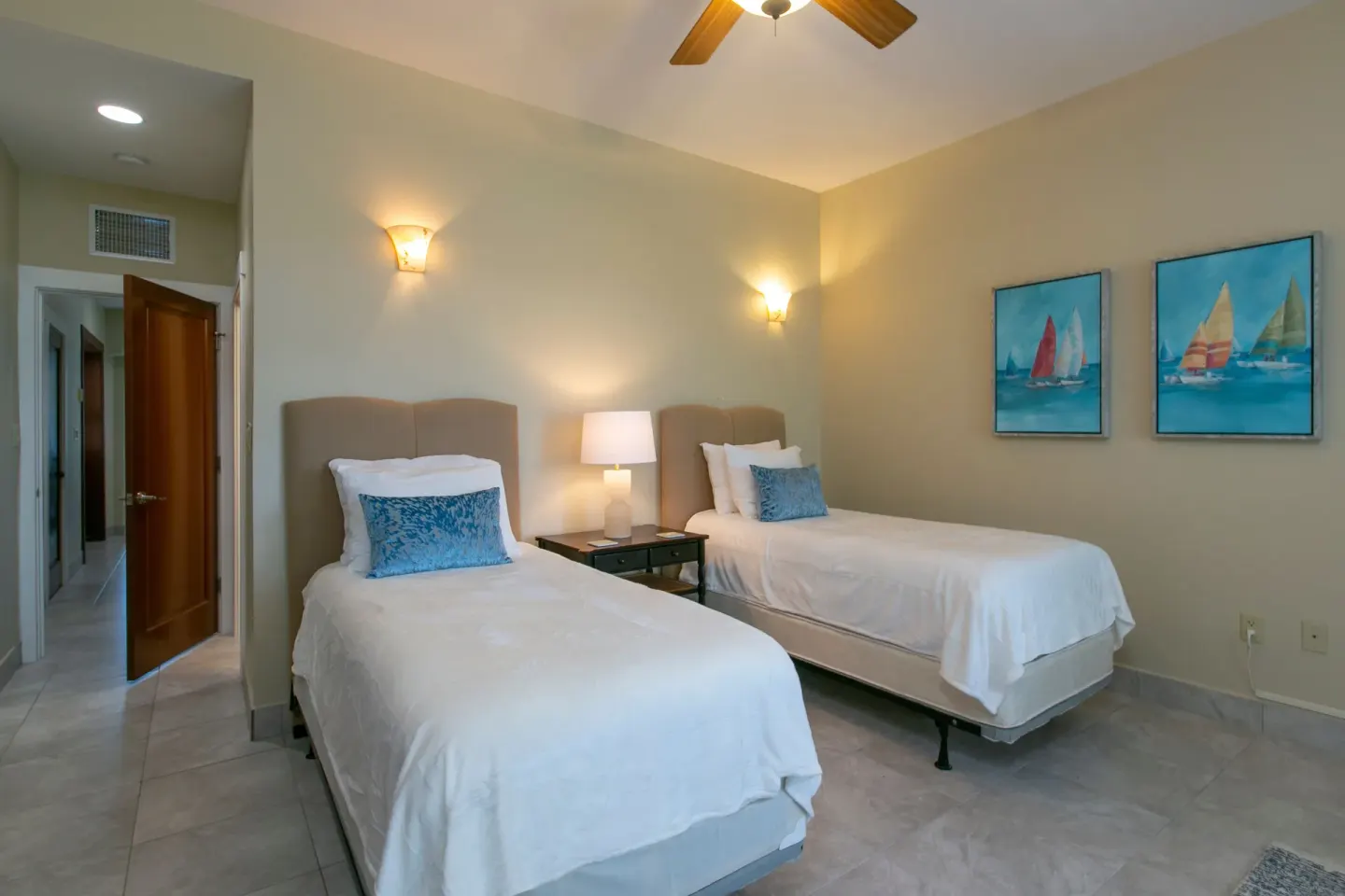 Twin bedroom with blue pillows, sailboat artwork, and wall sconces at The Hills, St John.