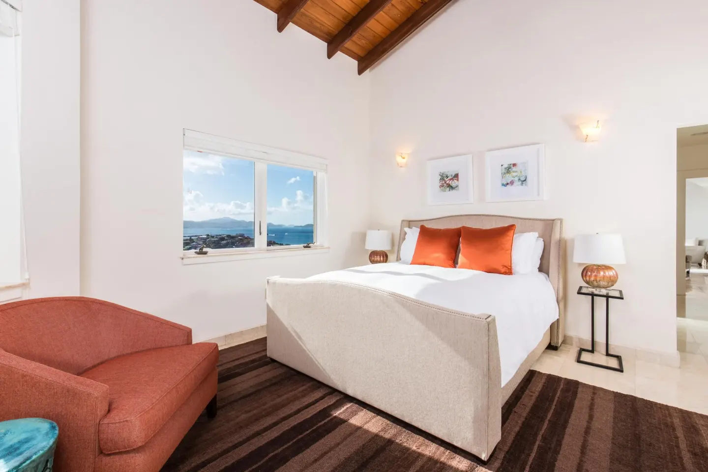 Bedroom with king bed, orange pillows, and a sea-view window at The Hills, St John.