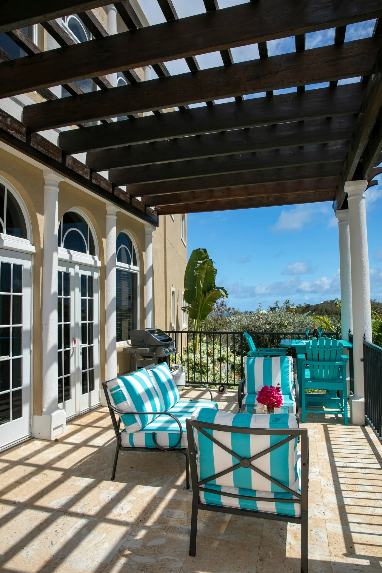 Shaded patio seating with striped cushions at Frangipani Villa, The Hills St John with tropical ambiance and privacy.