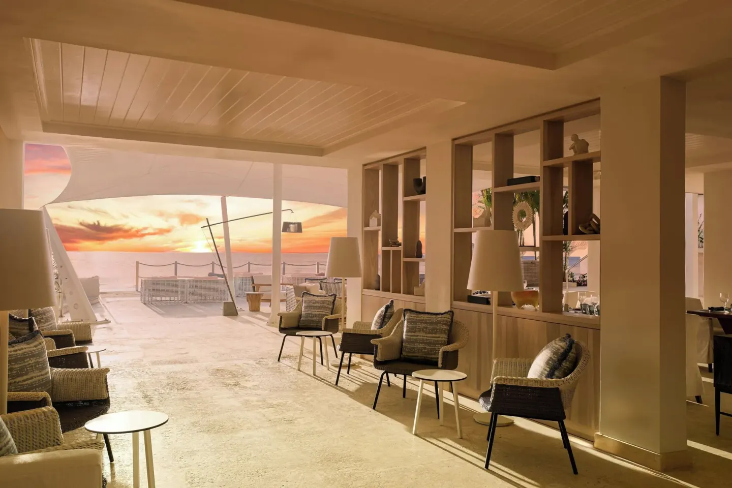 Covered lounge seating opens to an ocean sunset at The House.