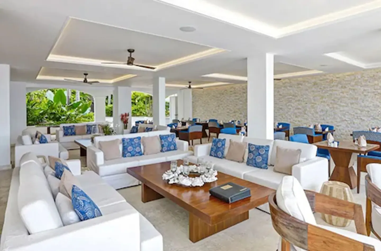 Open lounge and dining area with white sofas and blue cushions at The House.