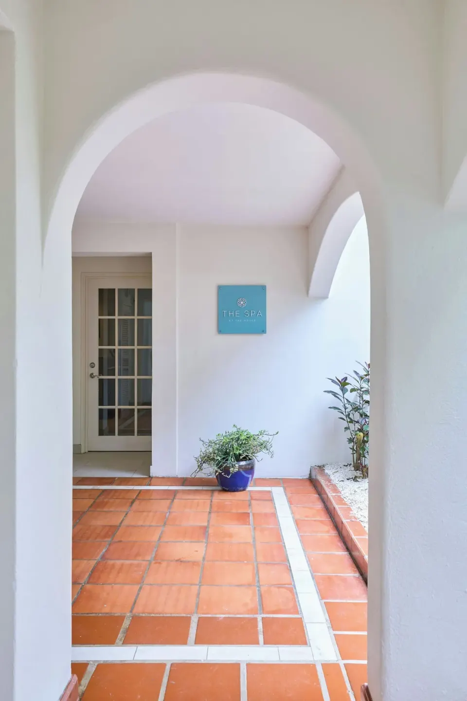 Arched spa entrance with terracotta floor tiles and a wall sign at The House.