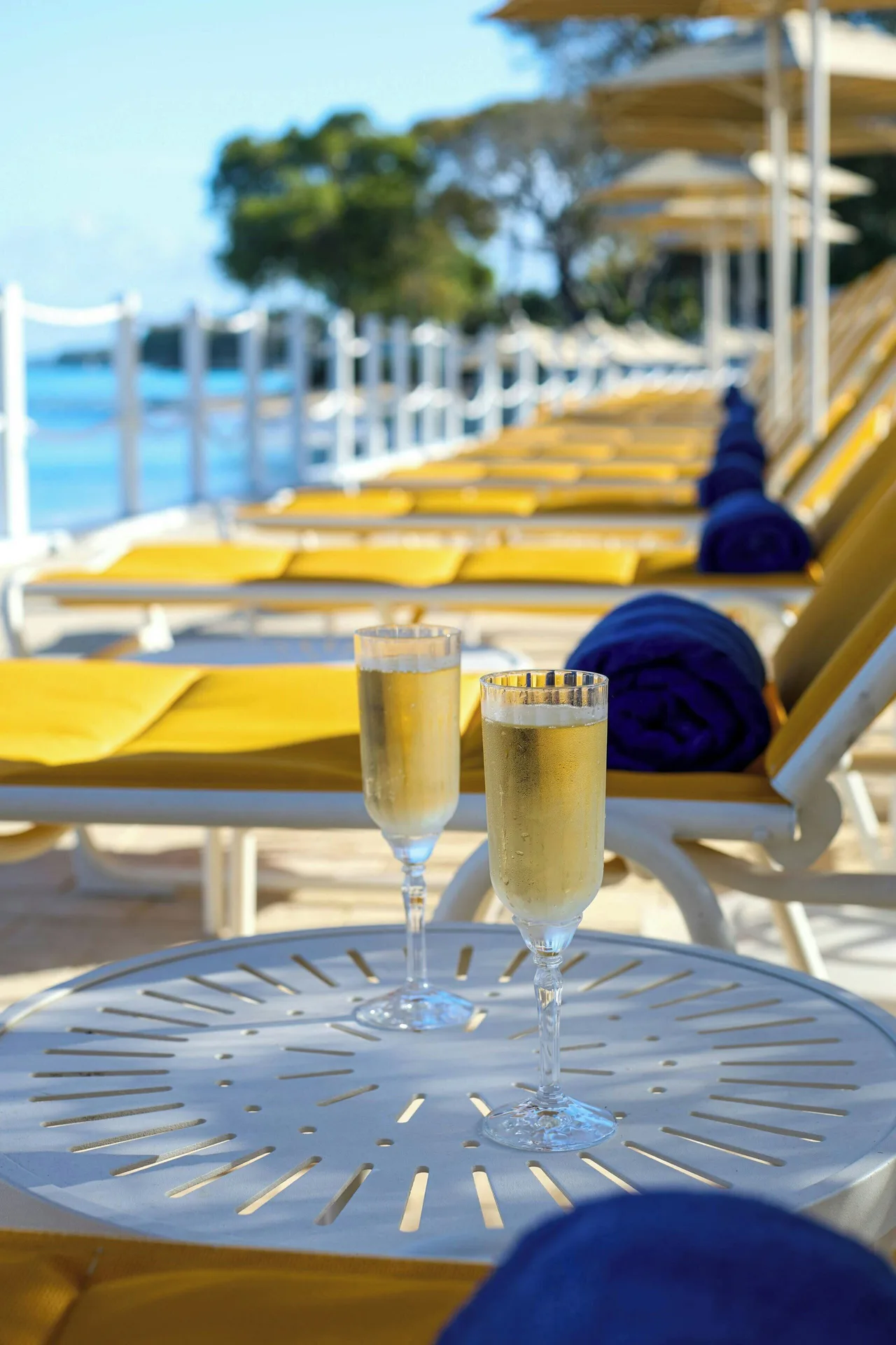Two sparkling drinks on a table beside yellow beach loungers at The House.
