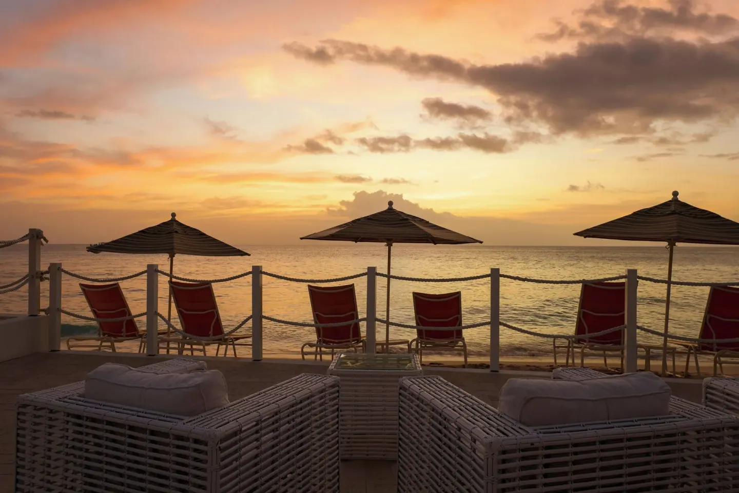 Beach chairs and umbrellas line the oceanfront at sunset at The House.