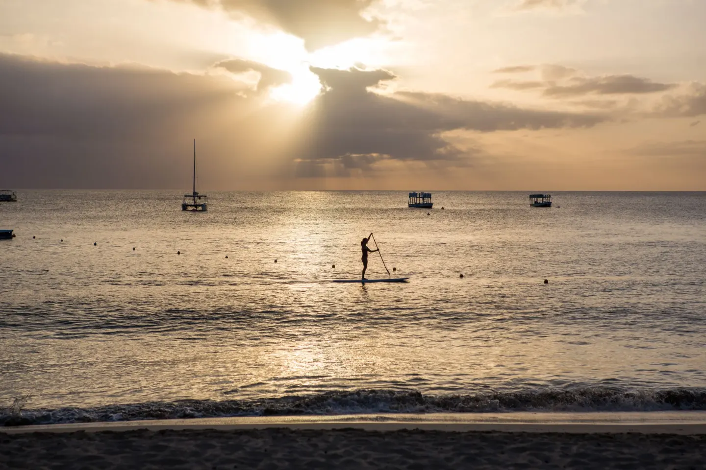 Paddleboarder silhouetted on the ocean at sunset near The House.