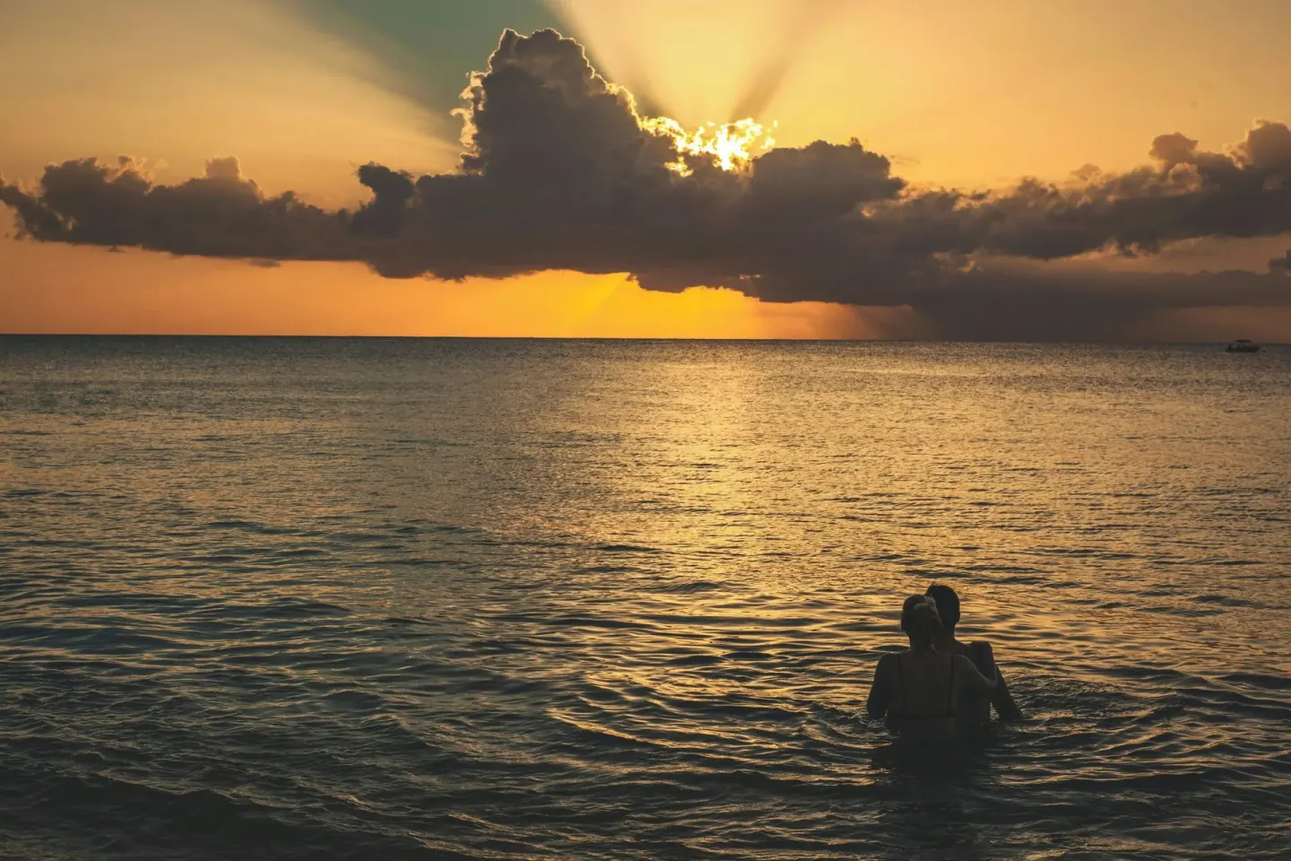 Two swimmers silhouetted in the sea at sunset near The House.