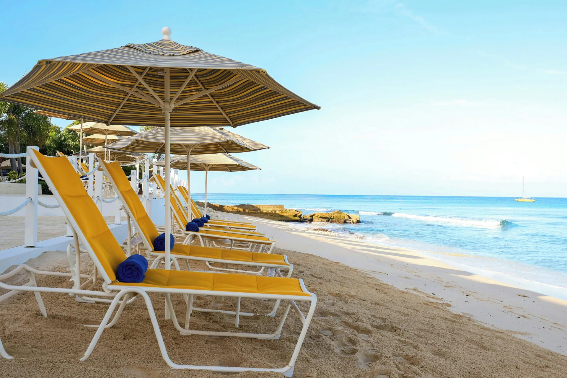 Yellow beach loungers under striped umbrellas facing the ocean at The House.