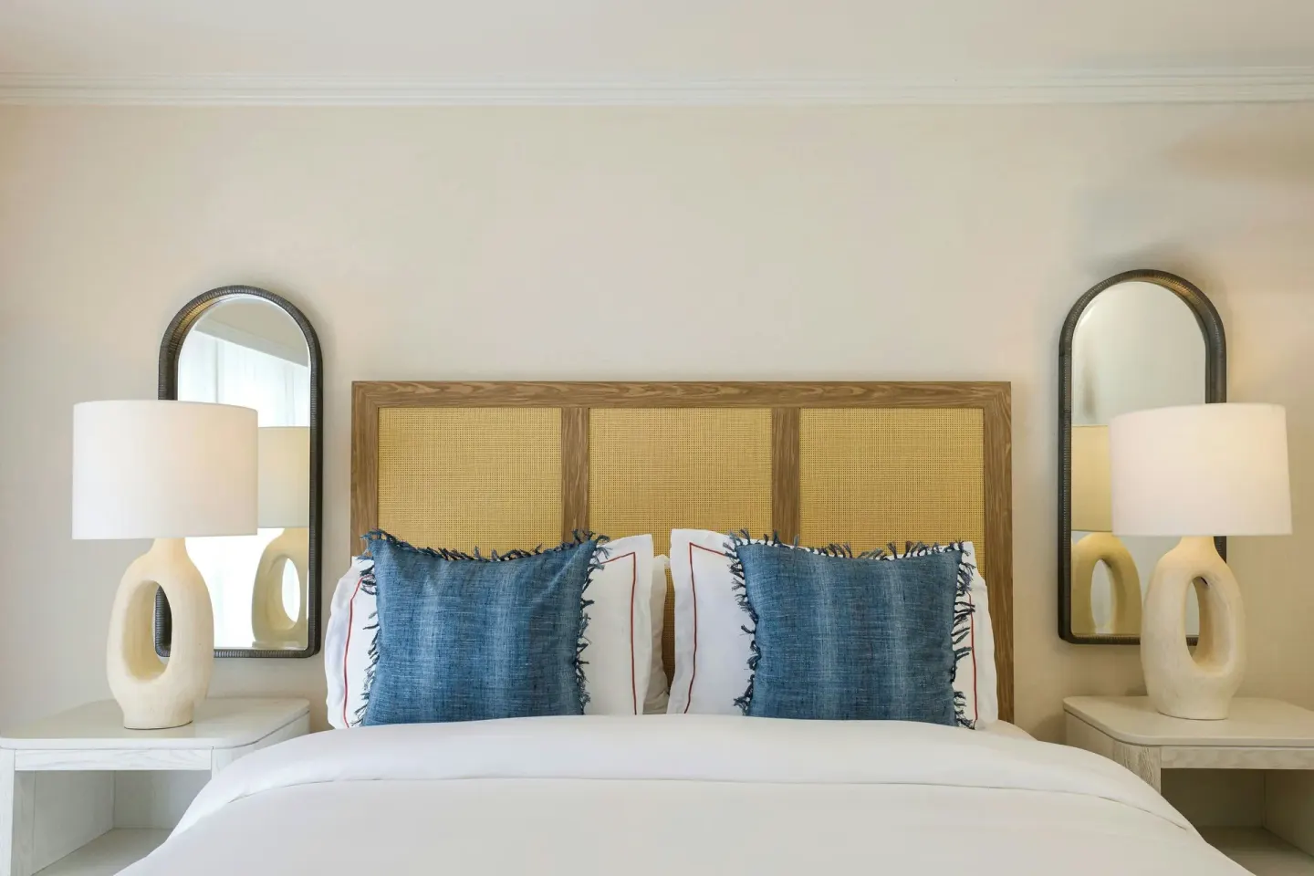 Junior Suite Garden View bed with woven headboard and blue pillows at The House.