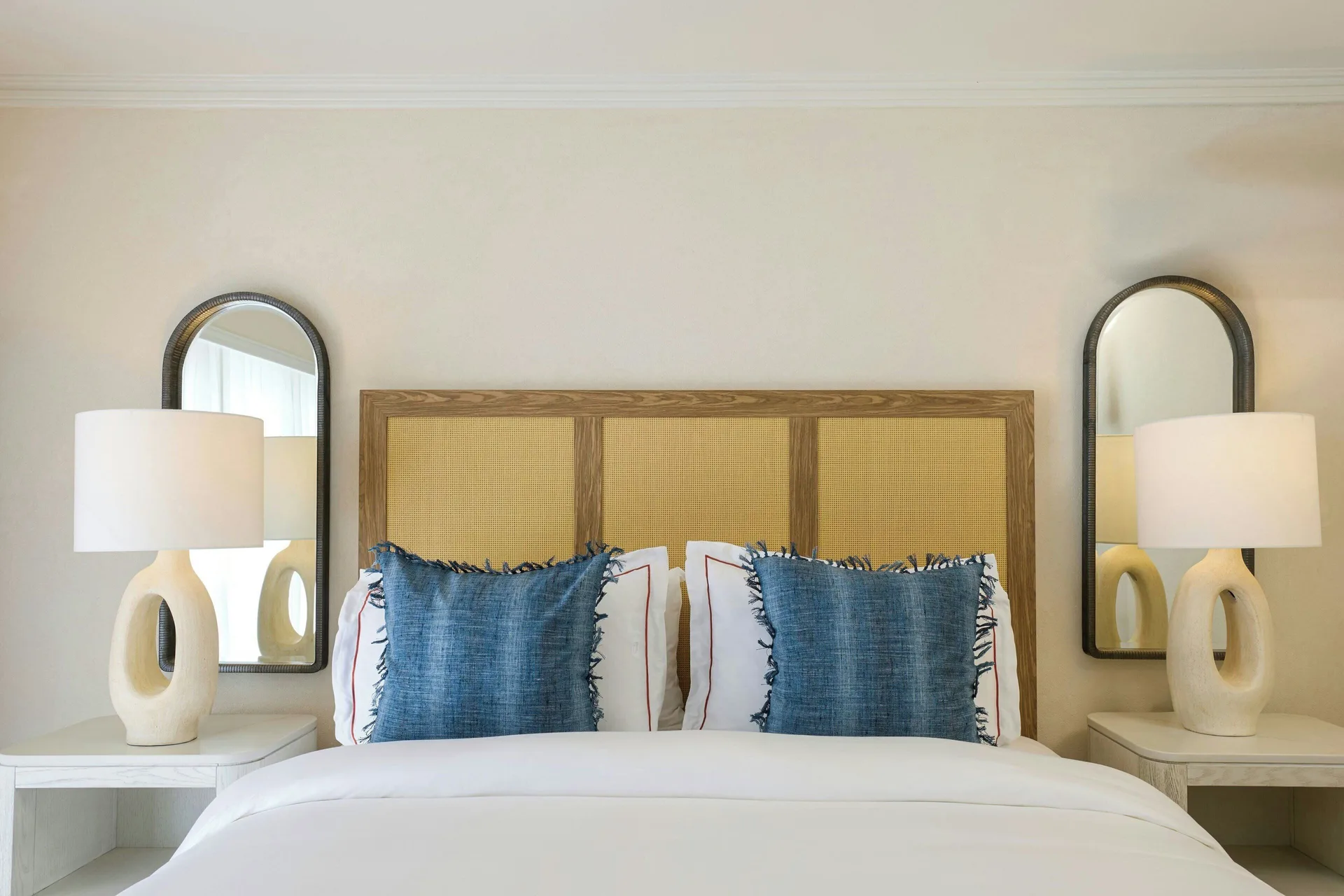 Junior Suite Garden View bed with woven headboard and blue pillows at The House.