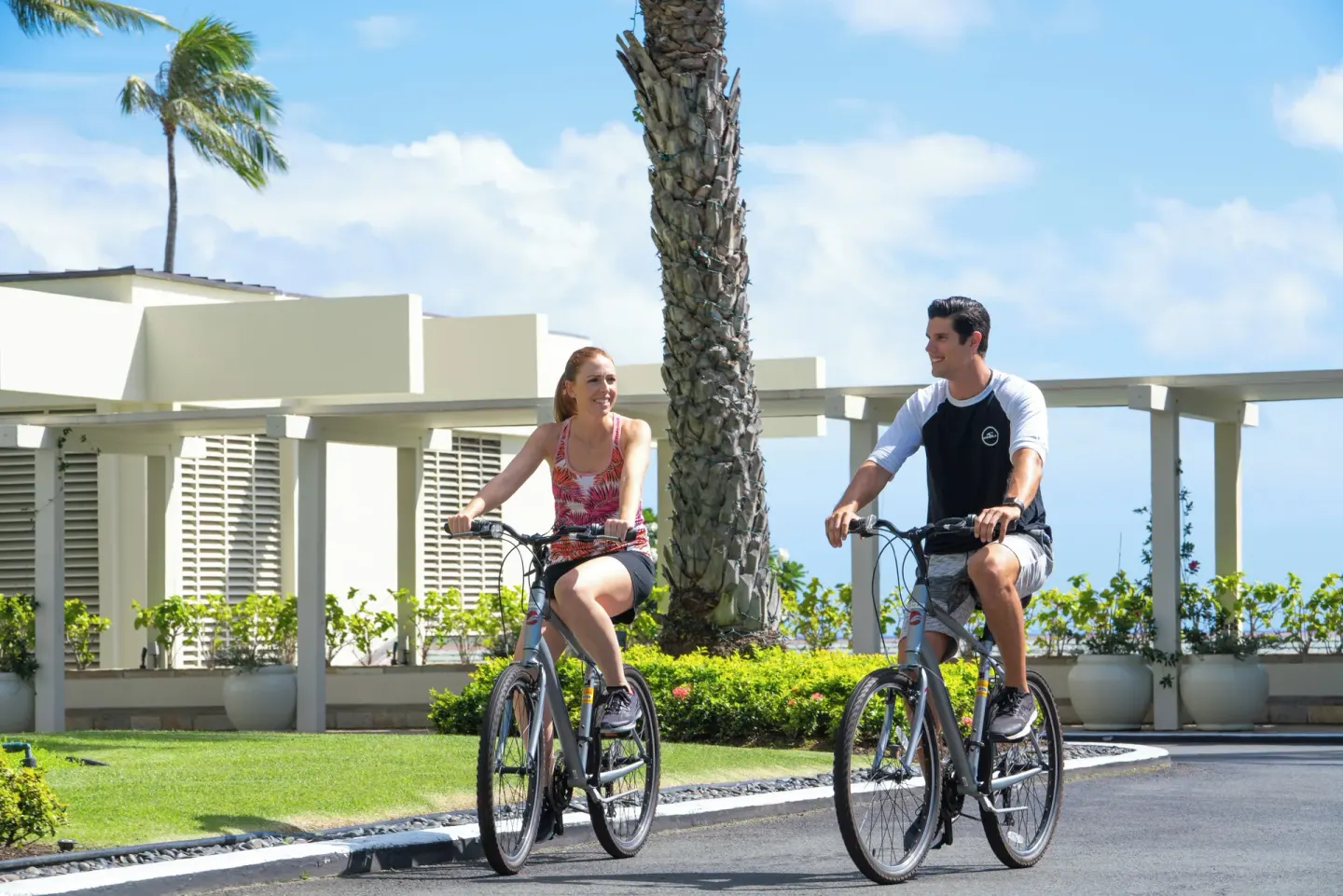 Guests riding bicycles along the resort drive at The Kahala Hotel & Resort.