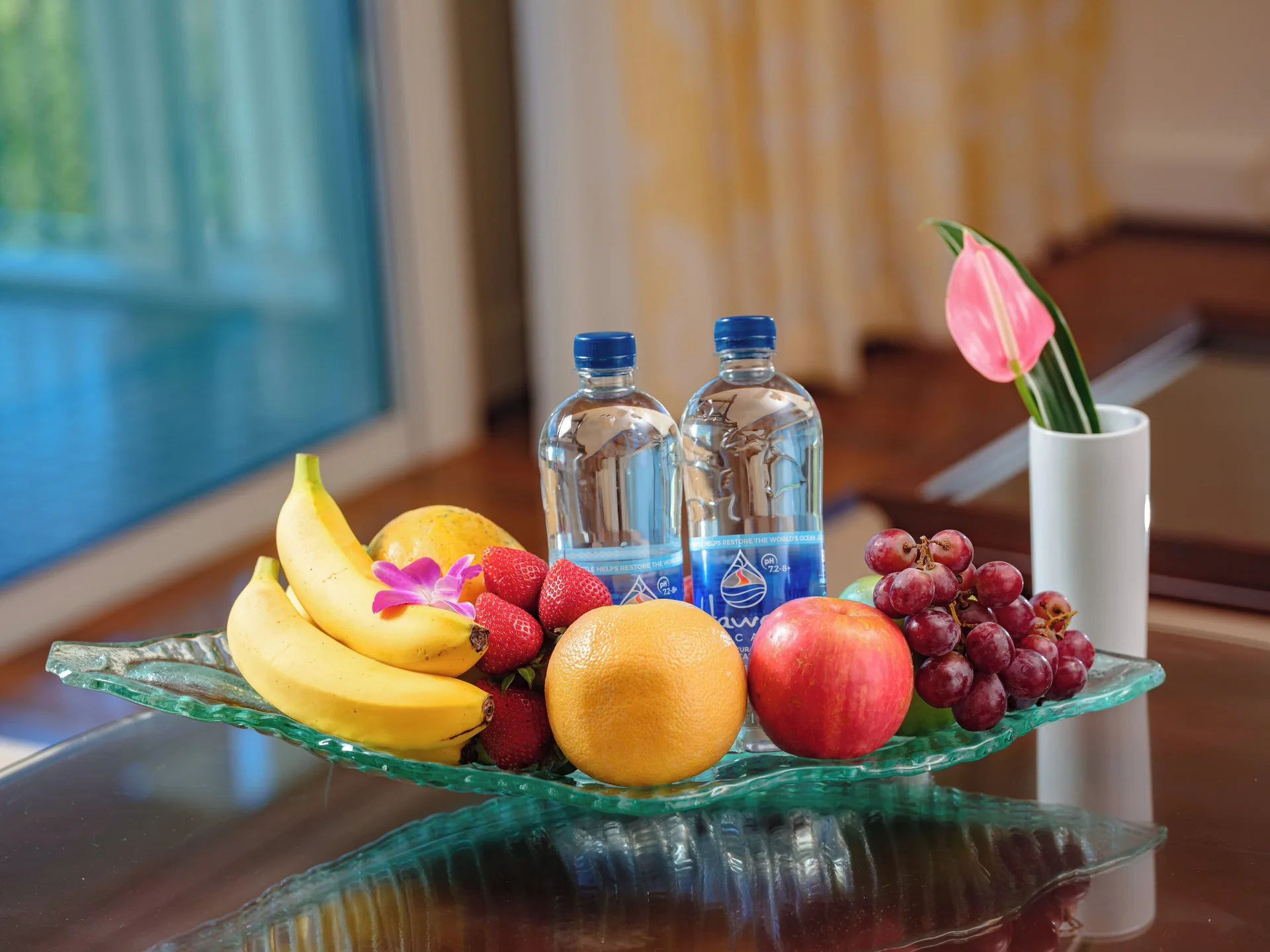 Fresh fruit, bottled water and a pink anthurium on a table at The Kahala Hotel & Resort.