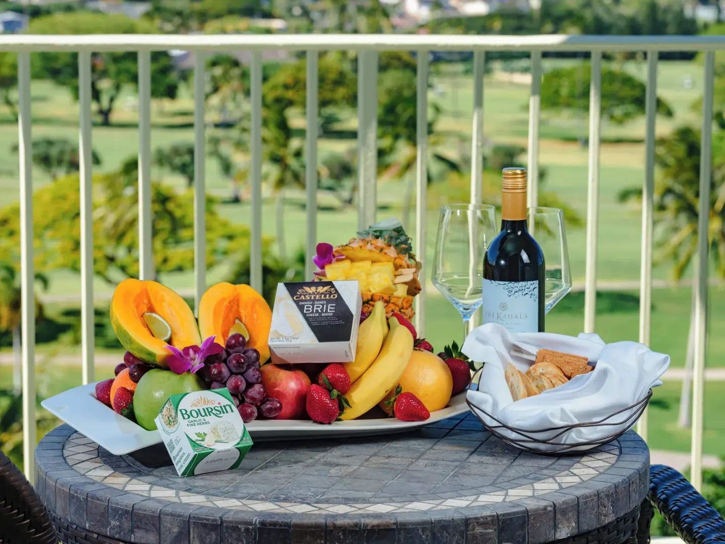 Fruit, cheese, wine, and crackers on a balcony table at The Kahala Hotel & Resort.