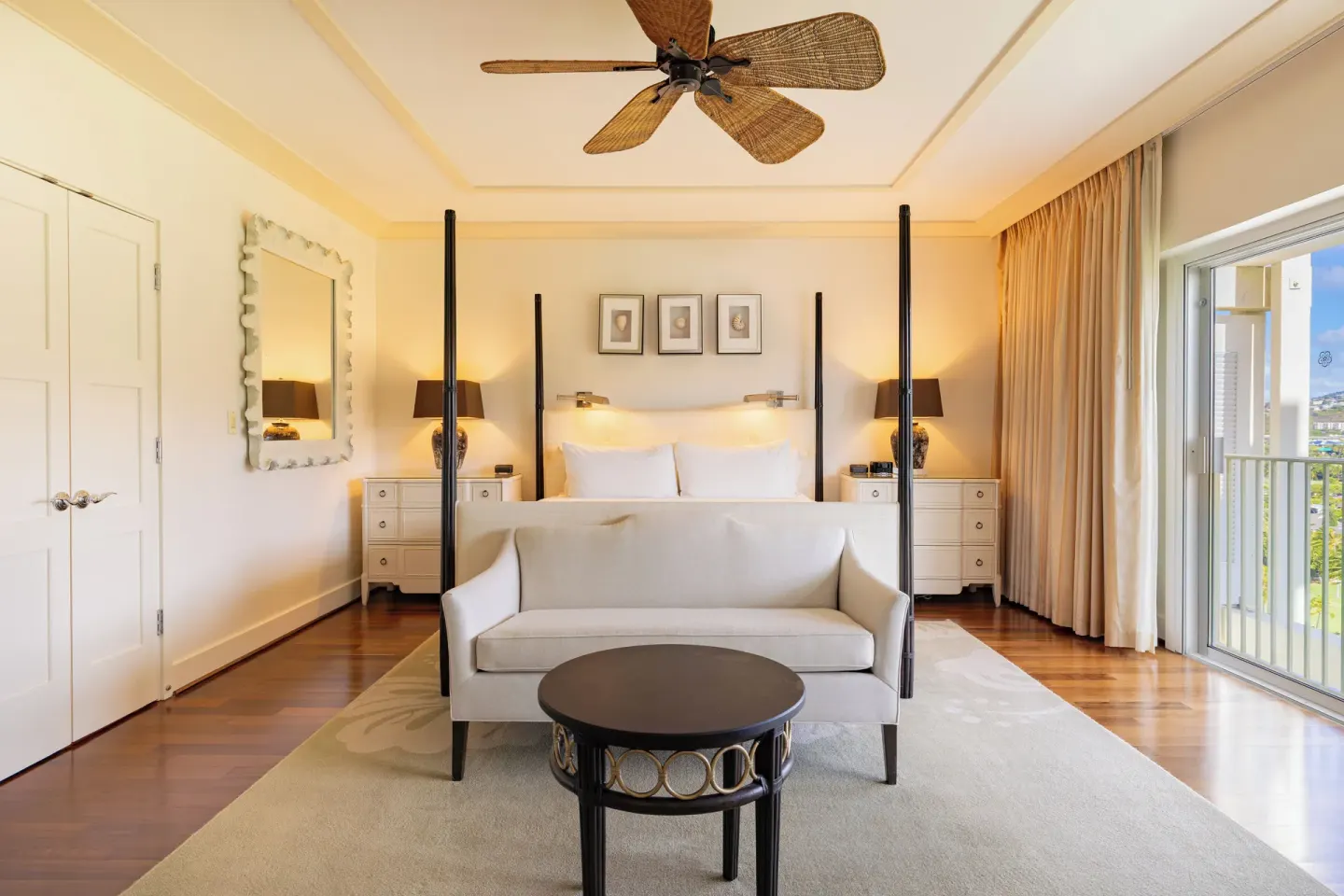 King bed guest room with sofa, balcony, and warm bedside lamps at The Kahala Hotel & Resort.