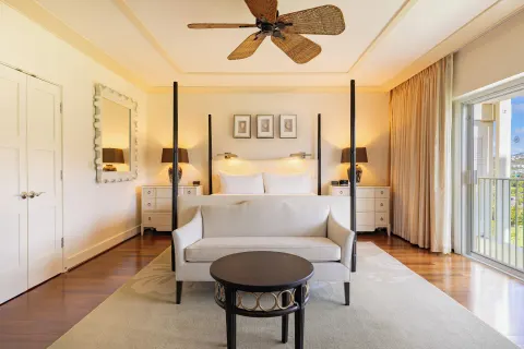 King bed guest room with sofa, balcony, and warm bedside lamps at The Kahala Hotel & Resort.