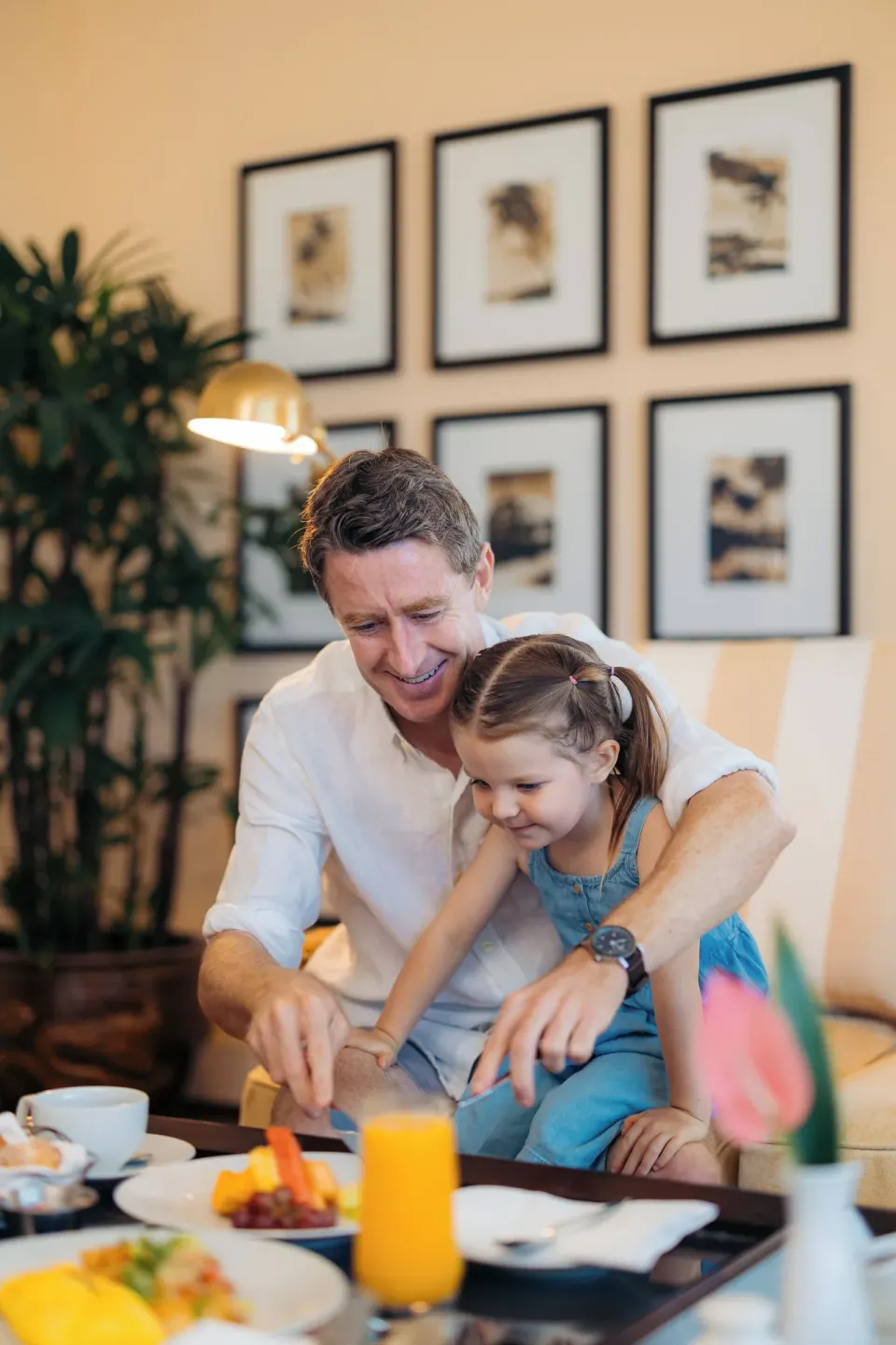 Father and child sharing breakfast in a guest room at The Kahala Hotel & Resort.